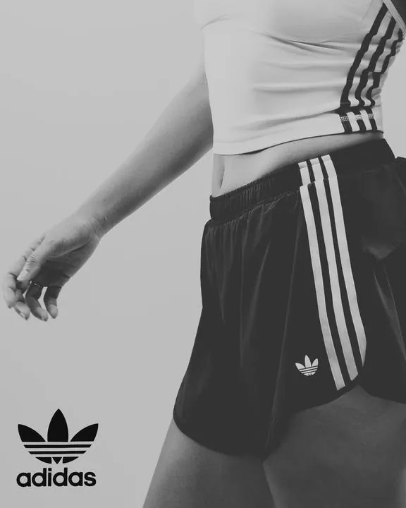 Detalle en blanco y negro de un short adidas de tres franjas