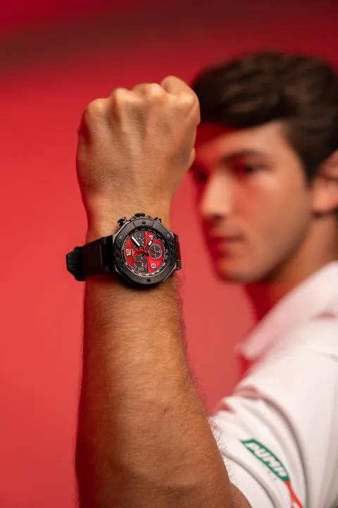 Reloj Tissot rojo y negro en la muñeca de un piloto, fondo rojo